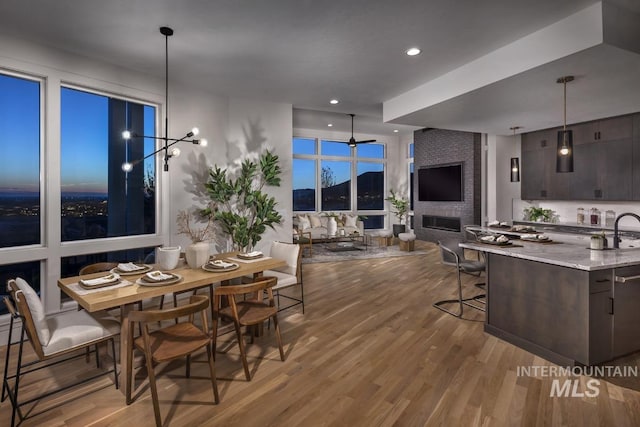 dining area with a notable chandelier, recessed lighting, wood finished floors, and a large fireplace