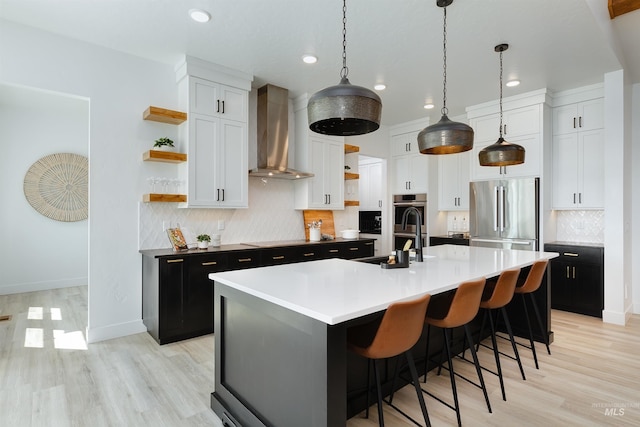 kitchen featuring open shelves, wall chimney exhaust hood, stainless steel appliances, dark cabinetry, and recessed lighting
