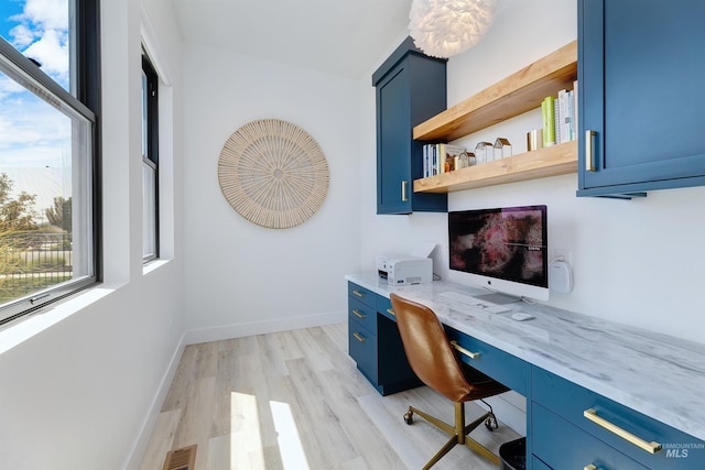 office space with built in study area, light wood-style floors, and baseboards