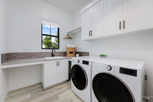 laundry room featuring cabinet space, washer and clothes dryer, and light wood-style flooring