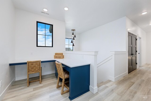 office area featuring light wood-style floors, baseboards, recessed lighting, and built in desk