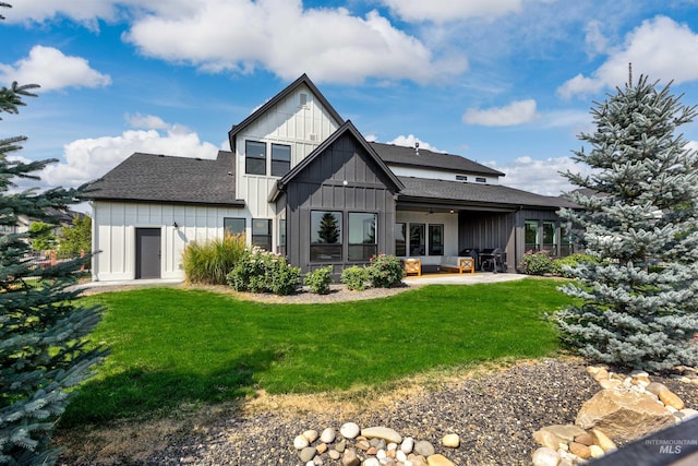 back of house with board and batten siding, roof with shingles, a patio, an outdoor hangout area, and a yard