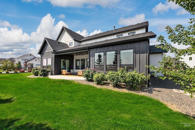 rear view of property featuring board and batten siding, a patio, ceiling fan, and a yard