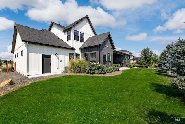 back of house featuring board and batten siding, a lawn, and roof with shingles