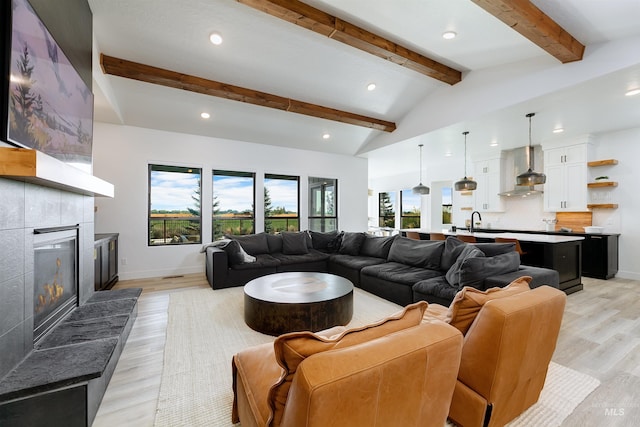 living room featuring recessed lighting, light wood finished floors, a tiled fireplace, and baseboards