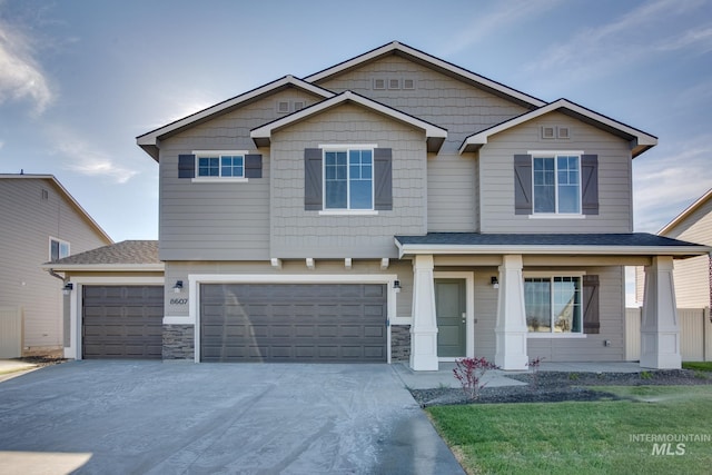 craftsman-style home with a garage, stone siding, roof with shingles, and concrete driveway