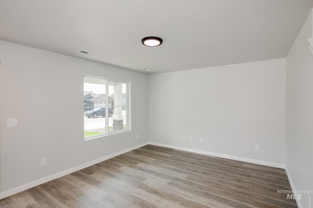 spare room featuring visible vents, baseboards, and wood finished floors