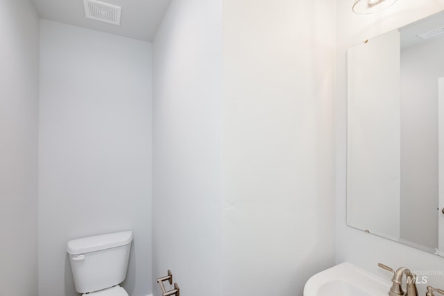 half bath featuring a sink, visible vents, and toilet