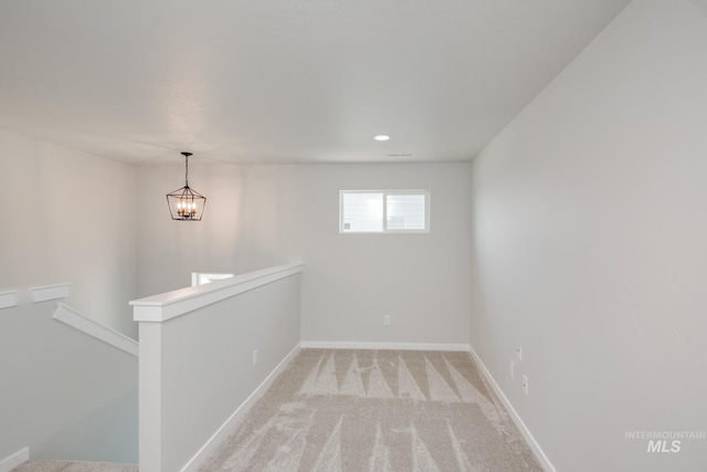 empty room with baseboards, light colored carpet, and an inviting chandelier