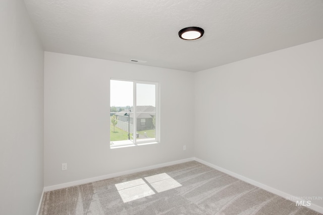 unfurnished room with visible vents, a textured ceiling, baseboards, and carpet floors