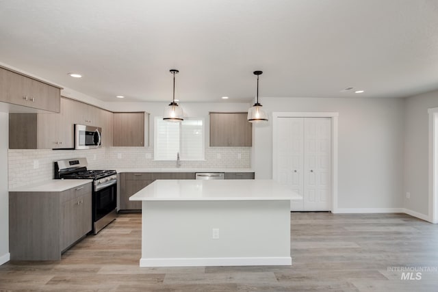 kitchen featuring light countertops, modern cabinets, light wood-type flooring, and appliances with stainless steel finishes