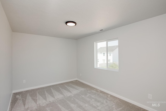 spare room with baseboards, light carpet, and visible vents