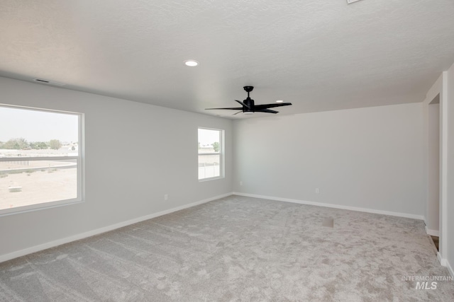 spare room with visible vents, baseboards, ceiling fan, carpet flooring, and a textured ceiling