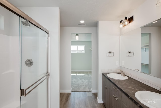 bathroom featuring a stall shower, wood finished floors, visible vents, and a sink