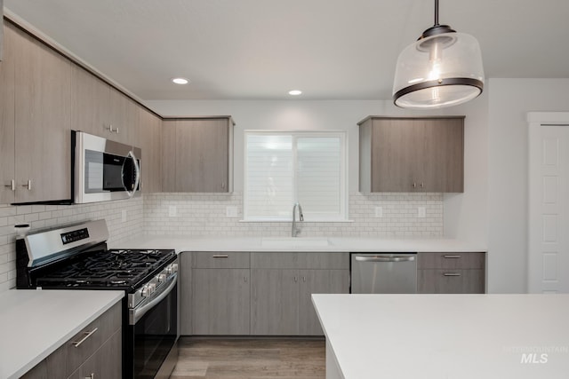 kitchen featuring stainless steel appliances, light countertops, light wood-style floors, and a sink