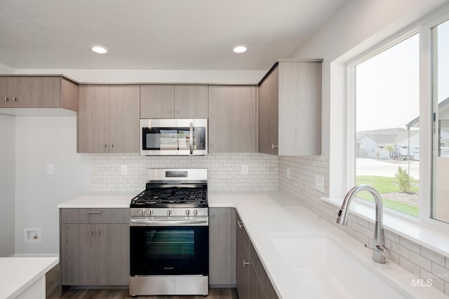 kitchen with recessed lighting, a sink, stainless steel appliances, light countertops, and tasteful backsplash