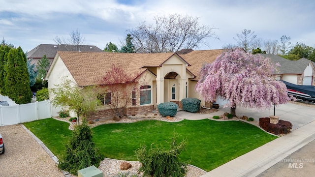 view of front of home with a front yard, fence, a shingled roof, and stucco siding