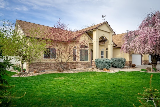 view of front of home featuring stucco siding, roof with shingles, a front yard, stone siding, and an attached garage