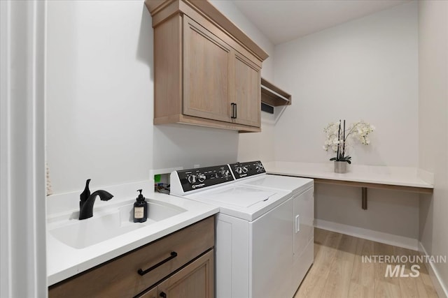 8749 W Suttle Lake Dr, Boise, ID 83714 - washroom featuring washing machine and clothes dryer, a sink, light wood-type flooring, baseboards, and cabinet space