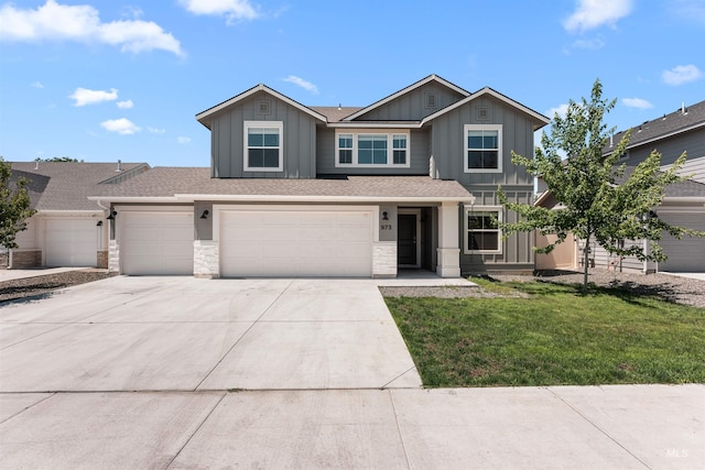 973 S Nautilus Ave, Boise, ID 83709 - view of front of home with board and batten siding, concrete driveway, stone siding, a front yard, and an attached garage