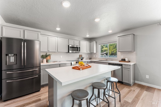 973 S Nautilus Ave, Boise, ID 83709 - kitchen featuring stainless steel appliances, gray cabinetry, backsplash, a kitchen breakfast bar, and light countertops
