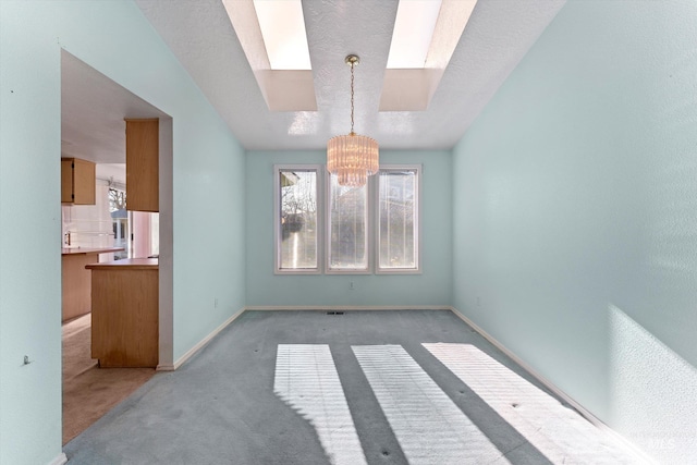 interior space with baseboards, a skylight, light colored carpet, and a notable chandelier