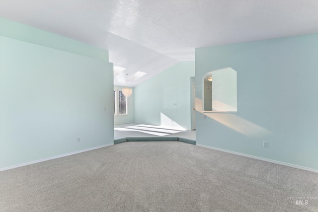 unfurnished room featuring carpet floors, lofted ceiling, a textured ceiling, and baseboards