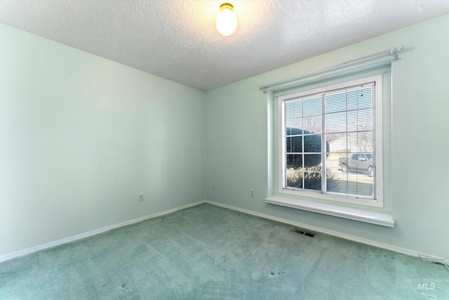 empty room featuring a textured ceiling, carpet, visible vents, and baseboards