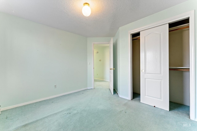 unfurnished bedroom with a textured ceiling, a closet, baseboards, and light colored carpet