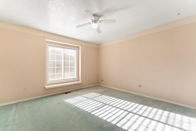 spare room featuring a textured ceiling, carpet floors, visible vents, and baseboards