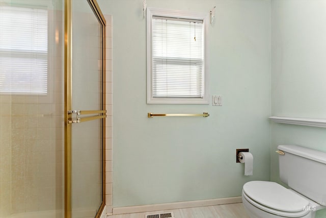 full bathroom featuring toilet, wood finished floors, visible vents, baseboards, and a stall shower