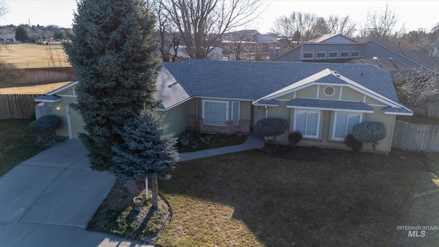 view of front of house featuring a front yard, fence, concrete driveway, and roof with shingles