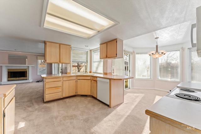 kitchen featuring light colored carpet, light brown cabinetry, plenty of natural light, a peninsula, and dishwasher