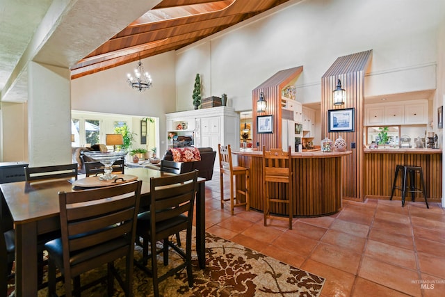 tiled dining area featuring an inviting chandelier, high vaulted ceiling, and wood ceiling