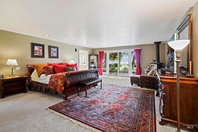 carpeted bedroom featuring access to exterior and a wood stove