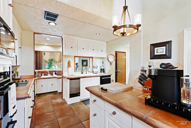 kitchen with pendant lighting, tile counters, white cabinetry, and sink