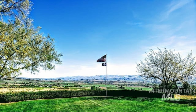 view of property's community with a lawn, a mountain view, and a rural view