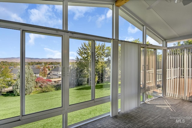 unfurnished sunroom with a wealth of natural light, a mountain view, and vaulted ceiling