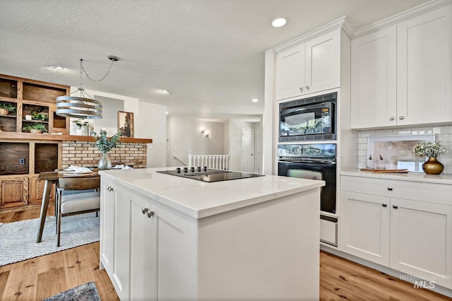 kitchen with tasteful backsplash, black appliances, a center island, and light wood finished floors