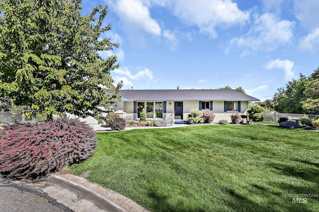 ranch-style house featuring a front lawn, fence, and brick siding