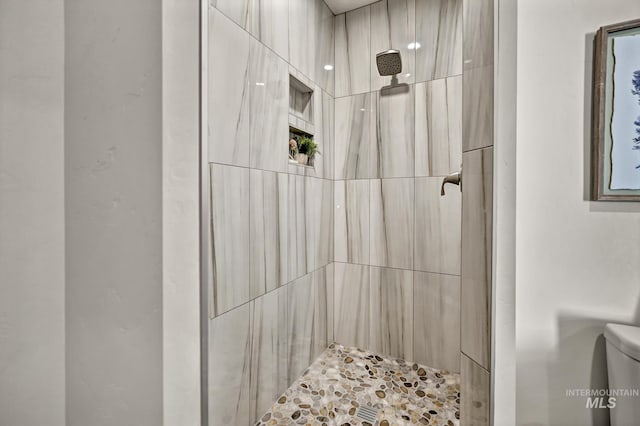 bathroom featuring toilet and a tile shower