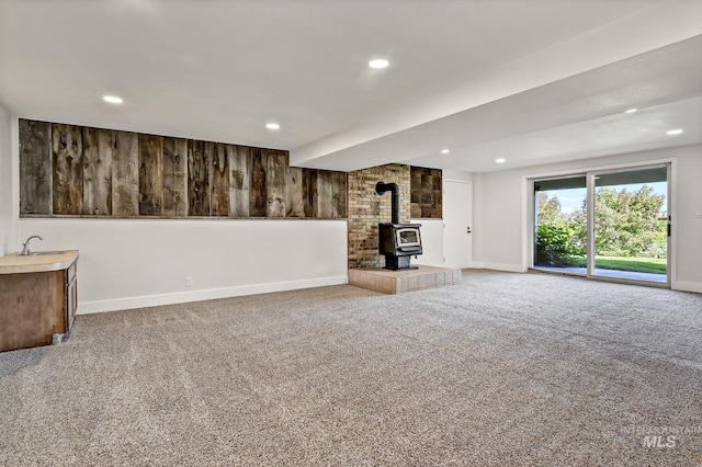 unfurnished living room with recessed lighting, carpet flooring, baseboards, and a wood stove