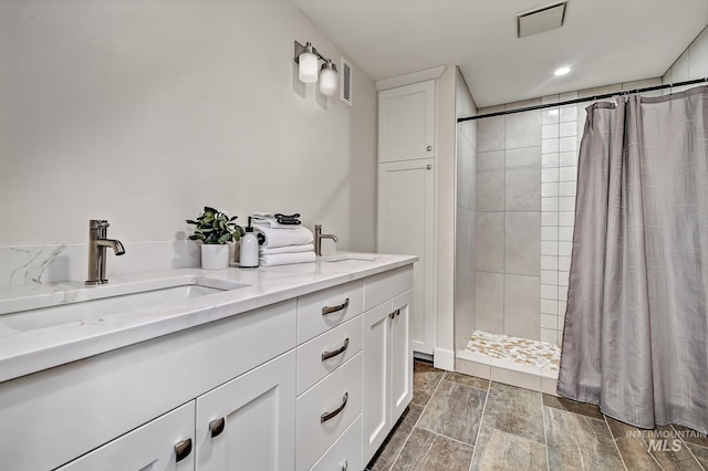 full bath featuring wood finish floors, visible vents, a tile shower, and a sink