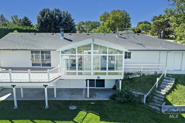 rear view of house featuring a yard, a sunroom, a shingled roof, stairs, and a patio area