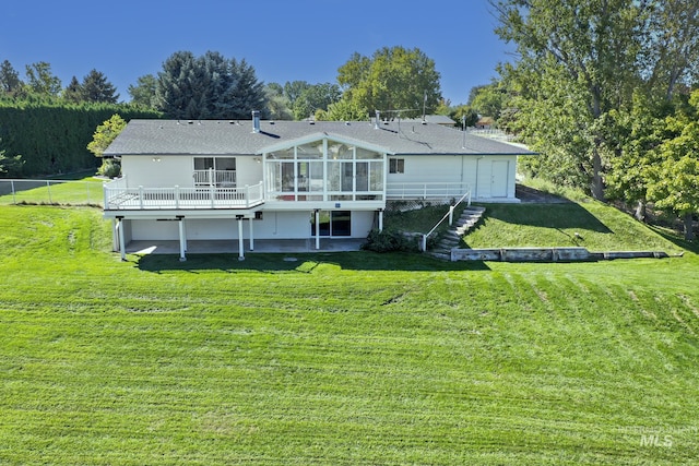 back of property featuring stairway, a lawn, a wooden deck, and a sunroom