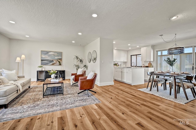 living area featuring recessed lighting, light wood finished floors, and a textured ceiling