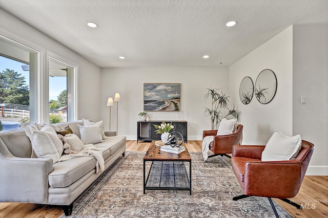 living area with recessed lighting, wood finished floors, baseboards, and a textured ceiling