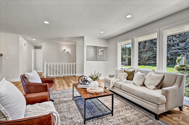 living room with visible vents, a textured ceiling, wood finished floors, recessed lighting, and baseboards