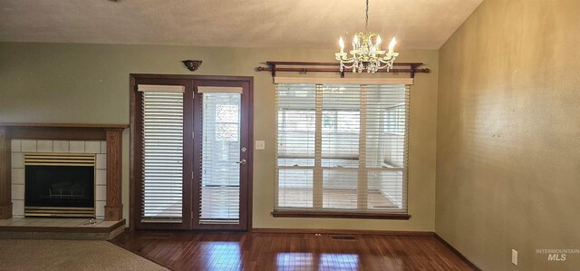 5720 N Oasis, Garden City, ID 83714 - unfurnished dining area with a chandelier, wood finished floors, a tiled fireplace, and baseboards