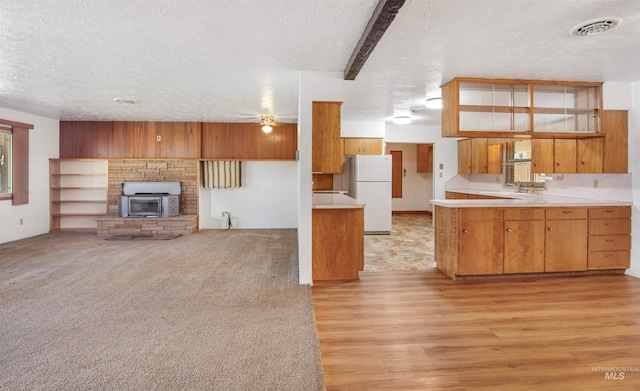 kitchen featuring freestanding refrigerator, light countertops, brown cabinets, visible vents, and a textured ceiling
